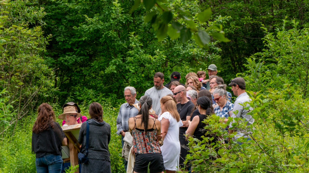 Visitors on a guided tour of the outdoor trail at ccdMalvina, surrounded by the lush vegetation of the Malvina site in Saint-Malo, Estrie